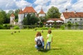 Kid walks on green meadow by old Blutenburg Castle, Munich, Germany