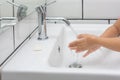 Kid washing hands in a white basin with a bar of white soap.