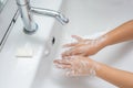 Kid washing hands in a white basin with a bar of white soap Royalty Free Stock Photo