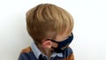 Handsome child in mask curiosity looking at camera white background coronavirus.