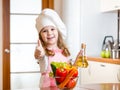 Kid weared as cook with vegetables at kitchen Royalty Free Stock Photo