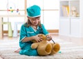 Kid weared doctor clothes playing with teddy bear Royalty Free Stock Photo