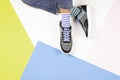 Kid wearing different pair of socks. Child foots in mismatched socks and colorful sneakers sitting on white background