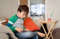 Kid wearing headset listening to music,Young sitting on sofa watching cartoons or playing games on tablet,Child boy using digital Royalty Free Stock Photo