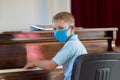 Kid wearing a mask and playing the piano at lesson and event. Kids back to school concept Royalty Free Stock Photo