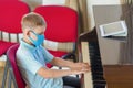 Kid wearing a mask and playing the piano at lesson and event. Kids back to school concept Royalty Free Stock Photo