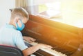 Kid wearing a mask and playing the piano at lesson and event. Kids back to school concept Royalty Free Stock Photo