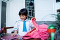 Kid wearing school uniform put some book in to her backpack