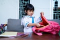 Kid wearing school uniform put some book in to her backpack