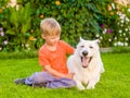 Kid and White Swiss Shepherd dog together on green grass Royalty Free Stock Photo