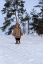 A kid in a winter fur coat, hat and felt boots in a snow-covered forest Royalty Free Stock Photo