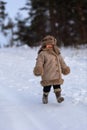 A kid in a winter fur coat, hat and felt boots in a snow-covered forest Royalty Free Stock Photo