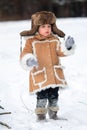 A kid in a winter fur coat, hat and felt boots in a snow-covered forest Royalty Free Stock Photo
