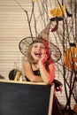 Kid in witch hat and costume leans on blackboard.