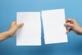 Kid and woman hands holding pieces of torn white paper sheet on light blue background Royalty Free Stock Photo