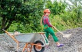 Kid working on construction site. teen girl takes out rubble from wheelbarrow. kid with shovel loading crushed stones Royalty Free Stock Photo