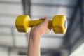 Kid working out with dumbbells in the sports hall of the club. Child hand holding yellow dumbbell on green background Royalty Free Stock Photo
