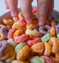 Kid's hand touching Colored Breakfast Cereal Close-up Royalty Free Stock Photo