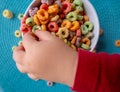 Kid's hand touching Colored Breakfast Cereal Close-up Royalty Free Stock Photo