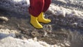 Kid in rainboots jumping in the ice puddle, slow motion