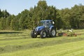 The kidding of shaken grass with blue tractor with Royalty Free Stock Photo