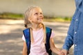 Kidnapping children concept. Good little gullible girl holding hand of unrecognizable man, looking at him and smiling Royalty Free Stock Photo