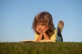 Kids adventure, freedom and carefree children. Cute kid reading book outside on grass.