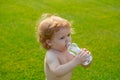 Kids baby drinking water. Child drinks bottled water from a bottle outdoor.