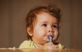 Kids baby eating with dirty face. Cheerful smiling child child eats itself with a spoon Baby eating with dirty face