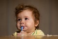 Kids baby eating with dirty face. Cheerful smiling child child eats itself with a spoon Baby eating with dirty face