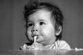 Kids baby eating with dirty face. Cheerful smiling child child eats itself with a spoon Baby eating with dirty face