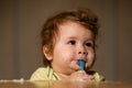 Kids baby eating with dirty face. Cheerful smiling child child eats itself with a spoon Baby eating with dirty face