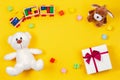 Kids baby toy background. Teddy bear, toy train, present gift box and other toys on yellow background Royalty Free Stock Photo