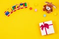 Kids baby toy background. Wooden train, stuffed puppy and present gift box on yellow background Royalty Free Stock Photo