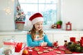 Kids bake Christmas cookies. Child in Santa hat cooking, decorating gingerbread man for Xmas celebration. Family preparing sweets