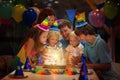 Kids birthday party. Child blowing candles on cake and opening presents on celebration Royalty Free Stock Photo