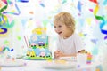 Kids birthday party. Child blowing out cake candle Royalty Free Stock Photo