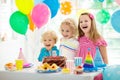 Kids birthday party. Child blowing out candles on colorful cake. Decorated home with rainbow flag banners, balloons. Farm animals Royalty Free Stock Photo