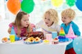 Kids birthday party. Child blowing out candles on colorful cake. Decorated home with rainbow flag banners, balloons. Farm animals Royalty Free Stock Photo