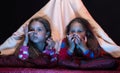 Kids in blanket tent wearing red jammies on black background