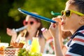 Kids blowing party horns on birthday in summer