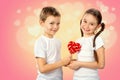 Kids, boy gives a little girl candy red lollipop in heart shape on pink background Royalty Free Stock Photo