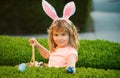 Kids boy hunting easter eggs. Easter kids boy in bunny ears hunting easter eggs outdoor. Cute child in rabbit costume