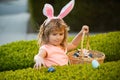 Kids in bunny ears on Easter egg hunt in garden. Child gathering eggs, easter egg hunt concept. Happy Easter kids face. Royalty Free Stock Photo