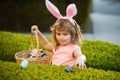 Kids in bunny ears on Easter egg hunt in garden. Child gathering eggs, easter egg hunt concept. Happy Easter kids face. Royalty Free Stock Photo