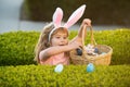 Kids in bunny ears on Easter egg hunt in garden. Child gathering eggs, easter egg hunt concept. Royalty Free Stock Photo