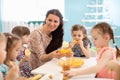 Kids and carer together eat fruit as a snack in the kindergarten, nursery or daycare Royalty Free Stock Photo