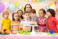 Kids celebrate birthday party and blow candles on festive cake