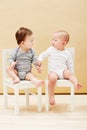 Kids, chair and baby boys for growth or child development in studio on an orange background. Youth, cute or adorable and