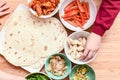 Kids choose what to add to homemade tortilla ingredients at childrens meal time at home in a kitchen